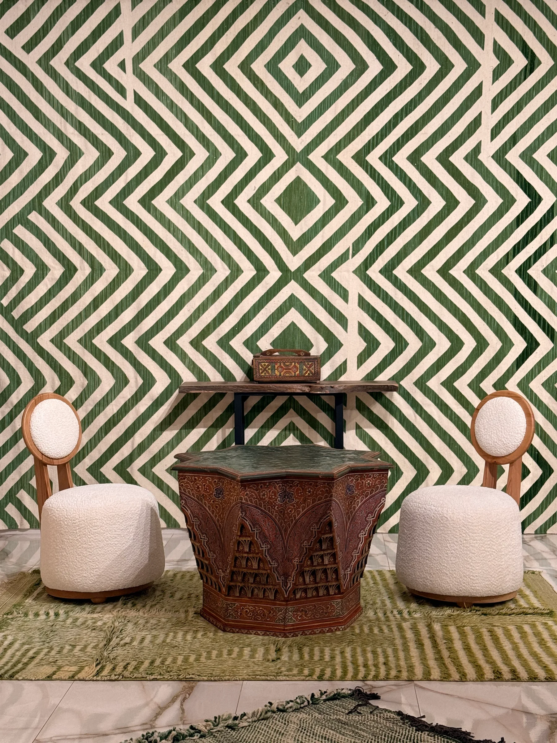 Chevron rug, boucle armchairs and carved table at Studio Bibi
